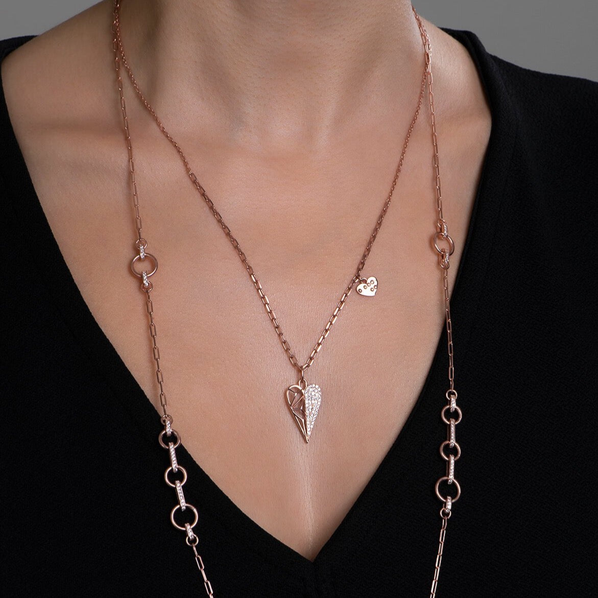 Silver heart shape pendant necklace on neck of a model.