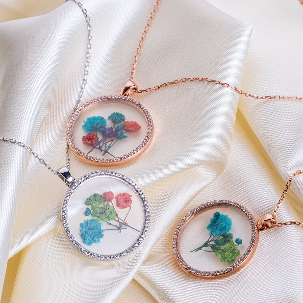 Silver necklaces with circle glass pendants with flowers  on a satin fabric, to show more realistic look.