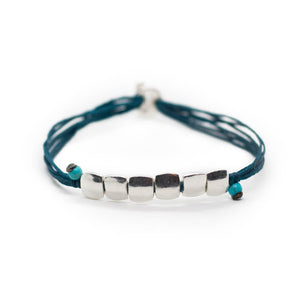 Custom design bracelet with petrol colour string with 6 square silver beads ending with two little turquoise beads.